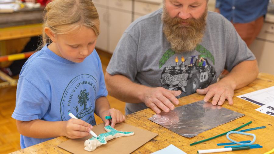 A Design for Industry student and first-grader use clay and markers to design a toy dolphin.