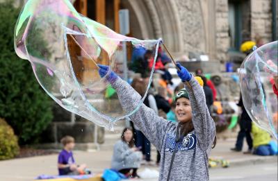 A smiling kid blows a gigantic bubble while watching the annual Homecoming Parade.