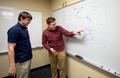 Assistant Professor Tyler Skorczewski, left, and student Ryan VandenBoomen talk over a problem in the Industrial Math class.