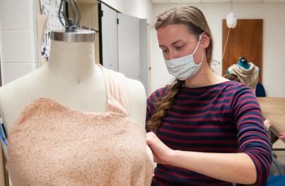 A student adjusts clothing in a fashion and retail lab.