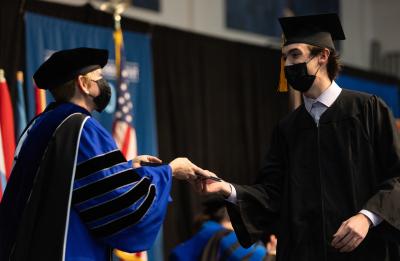 Chancellor Katherine Frank greets a graduate while handing him his diploma.
